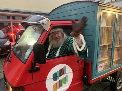 Büchertisch-Helfer Frieder winkt in Nikolaus-Kostüm aus dem Fenster des Berliner Büchertaxis